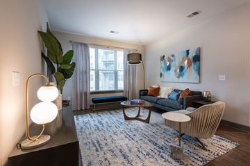 Raleigh apartment for rent - A living room with a blue rug and a large painting on the wall.