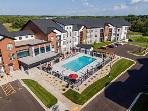 Janesville apartment for rent - A large building with a pool in front.