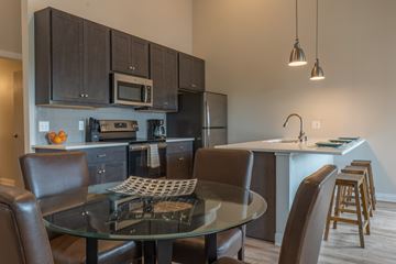 Waunakee apartment for rent - A modern kitchen with dark brown cabinets and a glass table.