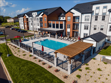 Janesville apartment for rent - A large building with a pool in front.