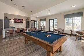 Janesville apartment for rent - A pool table is in the middle of a room with a bar and chairs.