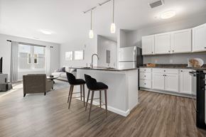 Nashua apartment for rent - a kitchen with white cabinets and an island with two chairs