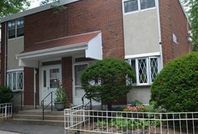 Roxbury townhouse for rent - A red brick house with a white fence in front.