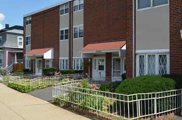 Roxbury townhouse for rent - A brick building with a white fence in front.