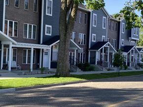 River Falls townhouse for rent - A tree stands in front of a two-story apartment building.