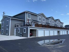 River Falls townhouse for rent - A row of houses with garages and a puddle in the foreground.