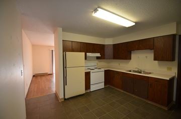 La Crosse apartment for rent - A kitchen with a white refrigerator, a white stove, and brown cabinets.