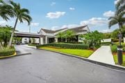 Pompano Beach apartment for rent - A road with a white building and palm trees on the side.