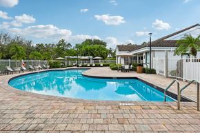 Pompano Beach apartment for rent - A swimming pool surrounded by a brick patio and a white fence.