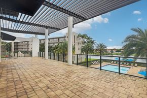 Miramar apartment for rent - A patio with a pool and a building in the background.
