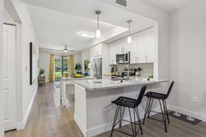 Melbourne apartment for rent - A kitchen with a white counter and black barstools.