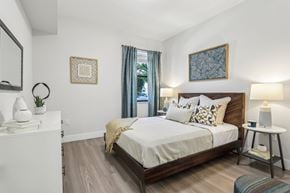 Melbourne apartment for rent - A bedroom with a large bed and a nightstand with a lamp.