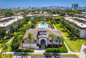 Miami apartment for rent - A large house with a pool surrounded by palm trees.