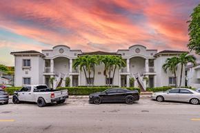Hialeah apartment for rent - A white building with a black car parked in front of it.