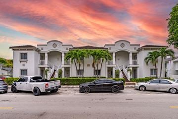 Hialeah apartment for rent - A white building with a black car parked in front of it.