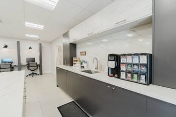 Hialeah apartment for rent - A modern kitchen with a white counter and a black fridge.