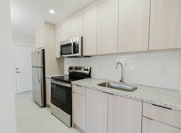 Miami apartment for rent - A kitchen with white cabinets and appliances.