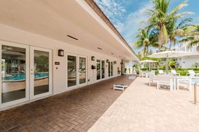 Miami apartment for rent - A sunny day at the poolside with a building in the background.