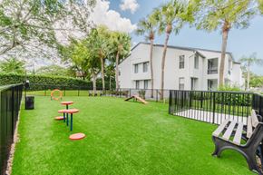 Coconut Creek apartment for rent - A playground area with a slide, picnic tables, and a bench in front of a white building.
