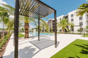 Margate apartment for rent - A pool area with a sunshade structure and palm trees.
