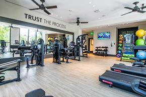 Miami apartment for rent - a gym with weights and cardio equipment and a sign saying trust the process