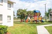 Miami apartment for rent - A playground with a blue roof and a slide is in front of a white building.