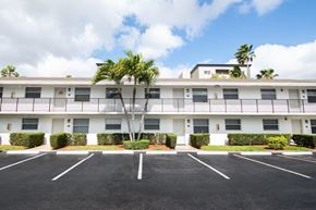 Hialeah apartment for rent - A large white building with a parking lot in front.