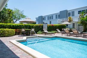 South Miami apartment for rent - A pool surrounded by chairs and a building in the background.