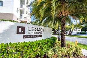 Miami apartment for rent - a sign for legacy at the rocks apartments in front of a palm tree