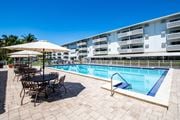 North Miami apartment for rent - A pool area with a table and chairs and umbrellas.