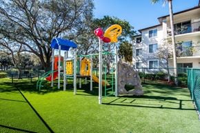 Davie apartment for rent - a playground with a slide and climbing equipment in front of an apartment building