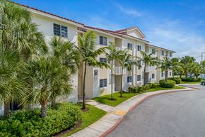 Davie apartment for rent - a building with palm trees in front of it on a street