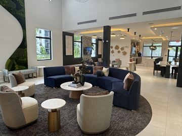 Margate apartment for rent - A large, modern living room with a blue sofa and a circular coffee table.