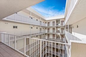 Miami apartment for rent - a balcony view of a building with white railing and a blue sky
