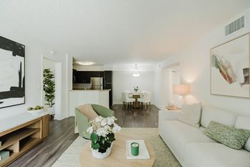Coconut Creek apartment for rent - A living room with a white couch, a coffee table with a vase of flowers, and a painting on the wall.