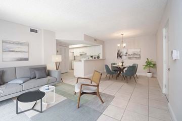 Miami apartment for rent - A living room with a grey couch, a wooden chair, and a dining table with chairs.