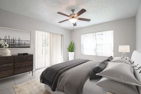 Miami apartment for rent - A bedroom with a bed, dresser, and ceiling fan.