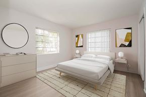 Pinecrest apartment for rent - a white bedroom with a bed and a mirror