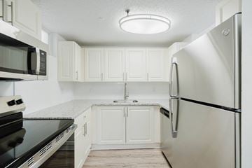 Miami apartment for rent - A kitchen with white cabinets and a black stove top oven.