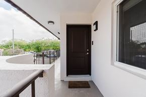 Miami apartment for rent - A brown door is on the right side of a white wall.