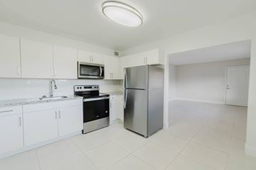 Miami apartment for rent - A kitchen with white cabinets and a stainless steel refrigerator.