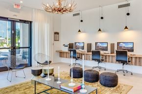 Hialeah apartment for rent - a lounge area with chairs and tables and televisions and a chandelier