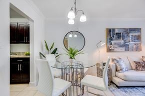 Miami apartment for rent - A modern dining room with a glass table and white chairs.