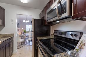 Miami apartment for rent - A kitchen with a black stove top oven and a black microwave above it.