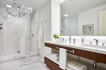 Floating bathroom vanities, double sinks with grohe finishes, and illuminated mirrors with frosted edges