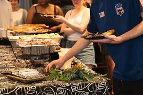 Arlington apartment for rent - A man in a blue shirt with an American flag on it is serving food from a tray.