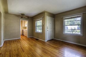Denver apartment for rent - the living room of an empty house with wooden floors and a ceiling fan