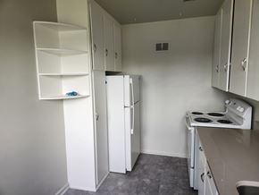 Denver apartment for rent - A small kitchen with a white fridge, white stove, and white cabinets.
