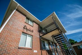 Denver apartment for rent - a brick apartment building with a staircase and a blue sky in the background