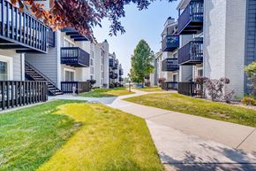 Arvada apartment for rent - A row of apartment buildings with a sidewalk and green grass.